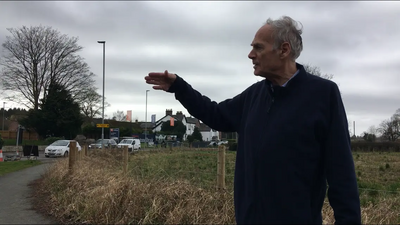 Cllr Ian Marks pointing towards traffic on Rushgreen Road