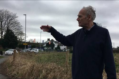 Cllr Ian Marks pointing towards traffic on Rushgreen Road